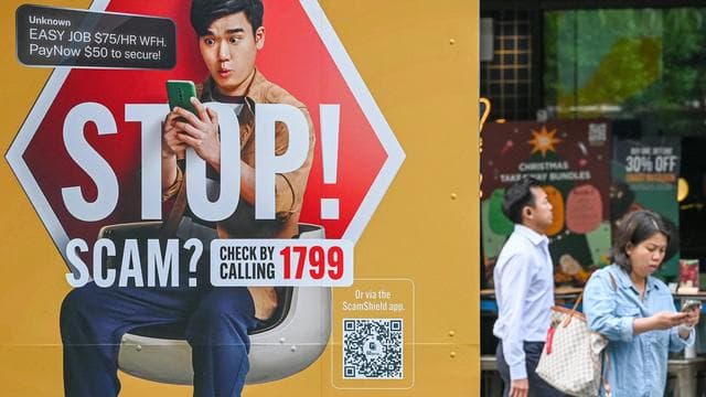 A street billboard showing a man on his phone inside a stop sign to warn of scam calls